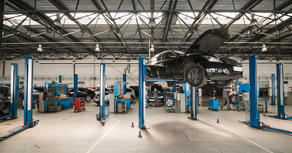 Oficina mecânica com utilitário leve em inspeção, ferramentas organizadas em painel e luz natural suave