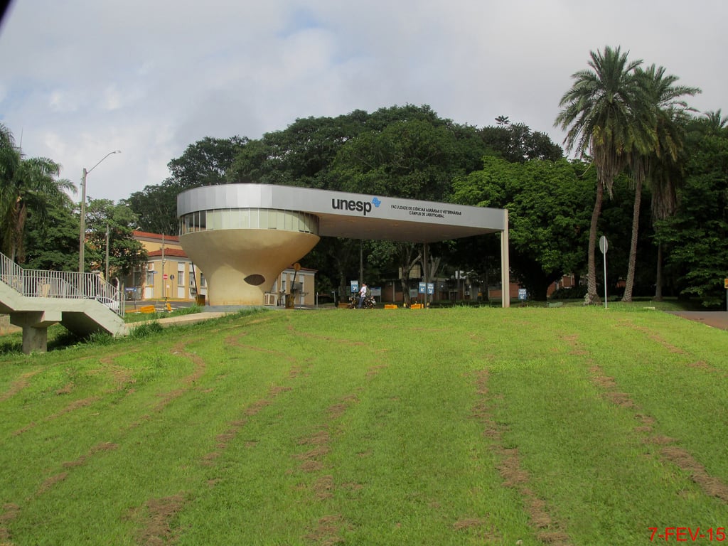 Entrada do campus da Unesp em Jaboticabal, com vegetação e arquitetura moderna ao fundo