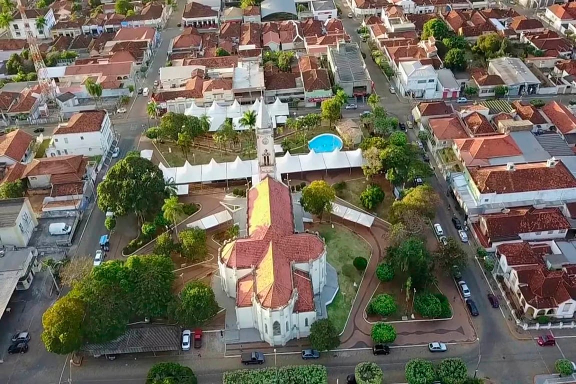 Vista urbana de Santa Albertina (SP), com igreja e praça central.