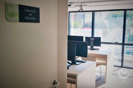 Laboratório de informática moderno, com fileiras de computadores e monitores ligados