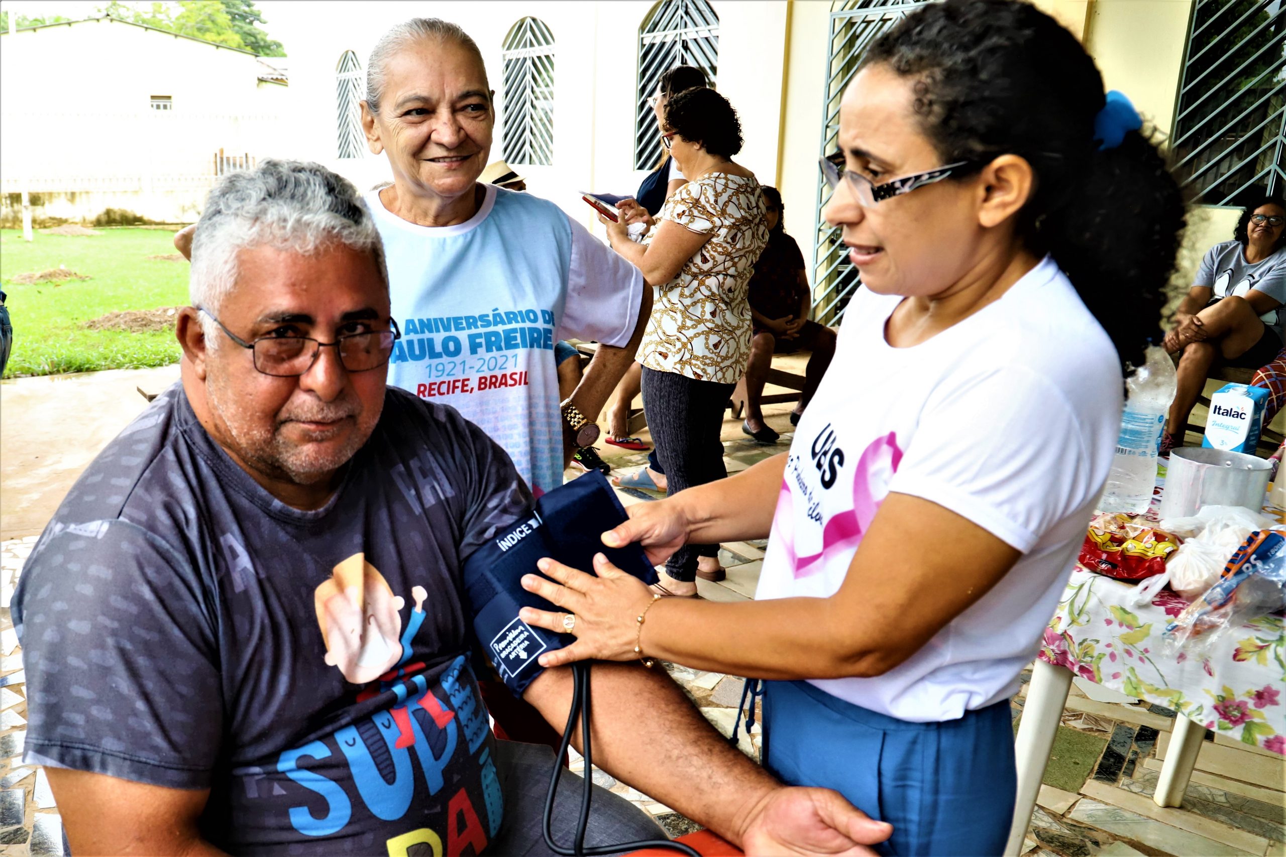 Agentes de saúde em atividade comunitária, com pranchetas e material educativo, em cenário urbano