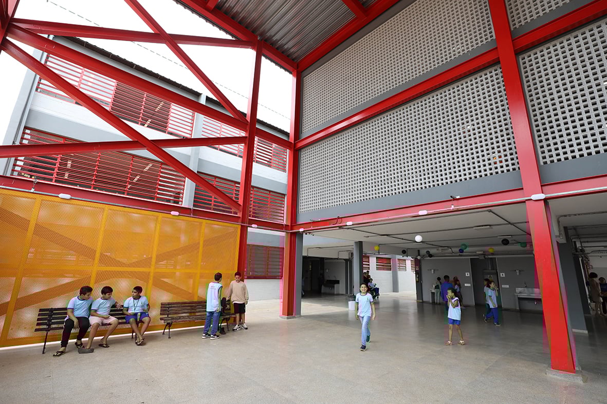 Corredor de escola pública iluminado, representando o ambiente de trabalho de apoio escolar.