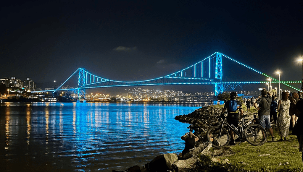 Vista aérea de Florianópolis com a Ponte Hercílio Luz iluminada ao entardecer
