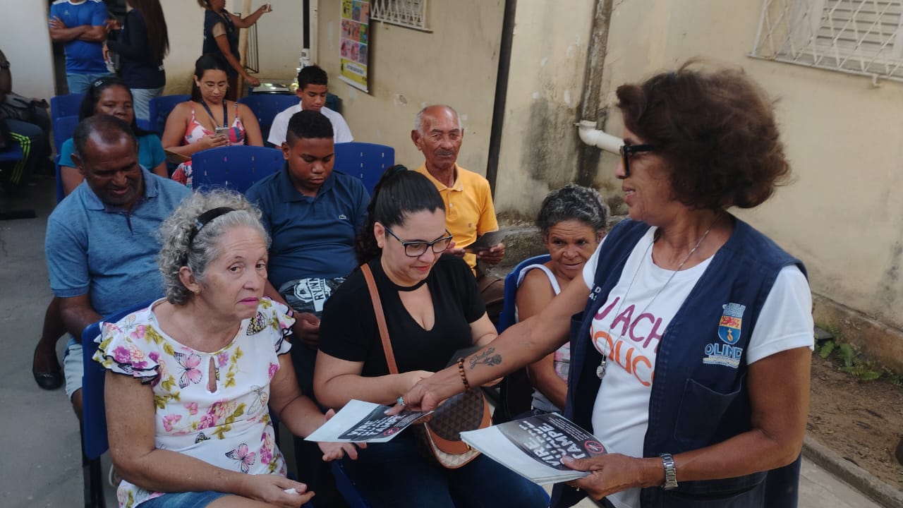 Agentes de saúde em ação, realizando orientação e entregando material informativo à comunidade