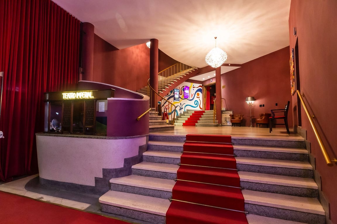 Interior de teatro moderno, com palco e escadaria de tapete vermelho