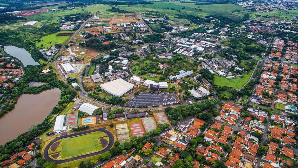 Vista aérea de campus universitário com prédios e áreas verdes, em Campinas SP