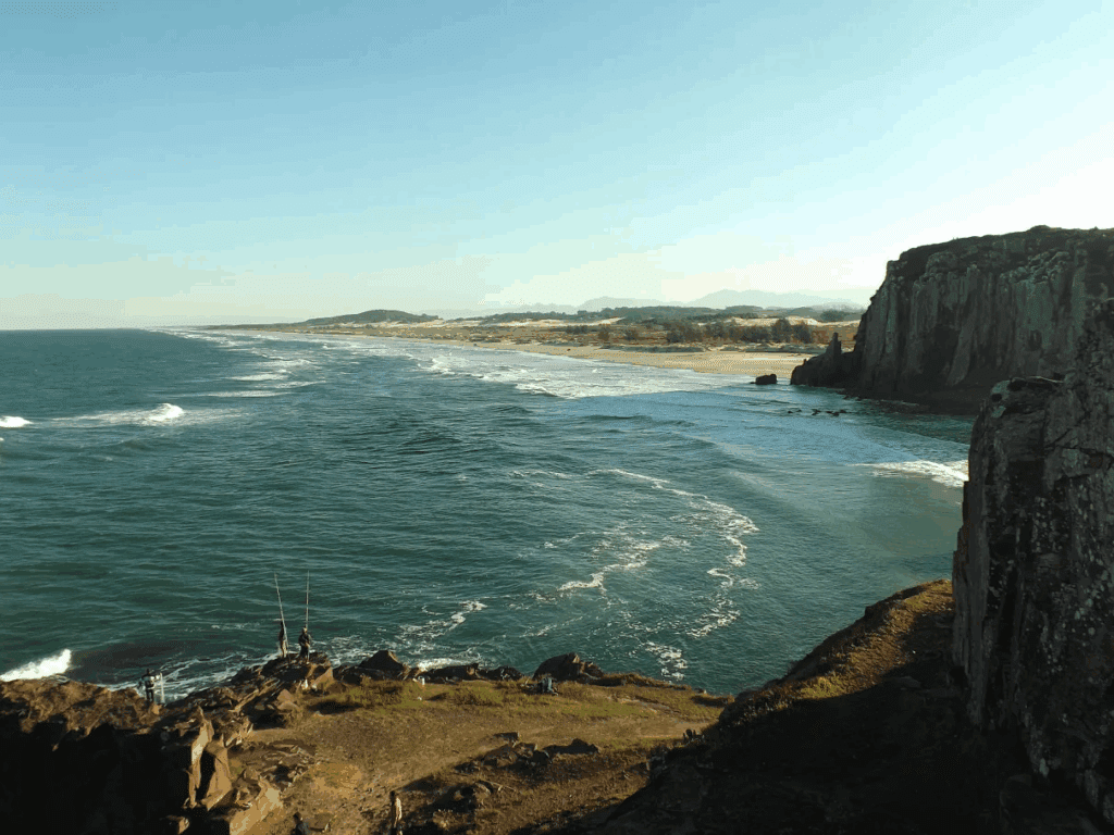 Vista panorâmica de Torres RS, com falésias e a Praia da Guarita ao fundo, céu azul e dia claro