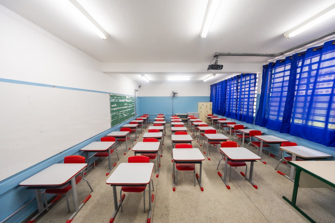 Sala de aula de escola pública no interior, com mesas, quadro e luz natural