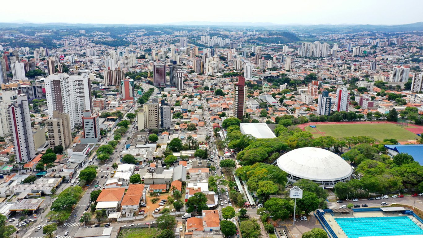 Vista aérea de Jundiaí ao entardecer, com prédios e áreas verdes