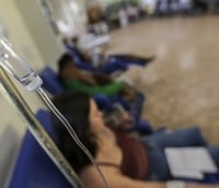 Recepção em unidade pública de saúde com pacientes aguardando e profissional uniformizado ao fundo