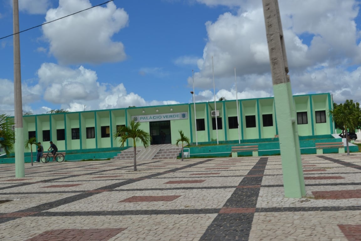 Prédio público em Irauçuba, Ceará, conhecido como “Palácio Verde”, pessoas na calçada, céu parcialmente nublado