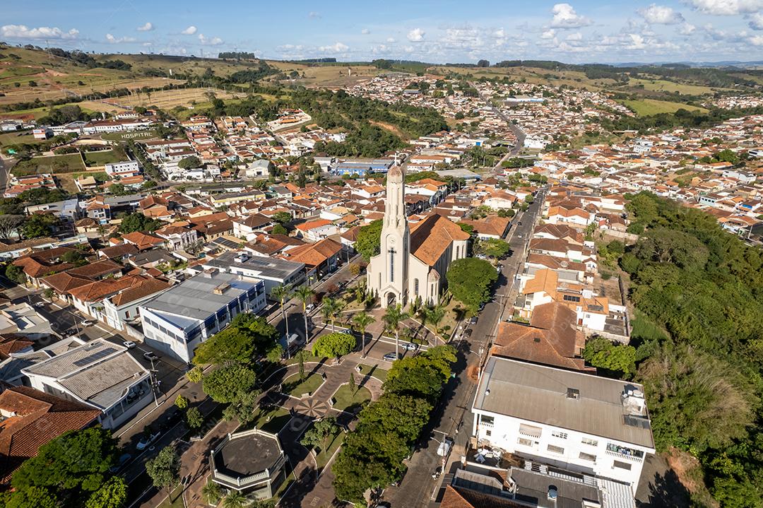 Vista aérea de uma cidade no Sul de Minas, com morros verdes ao fundo e área urbana ao centro