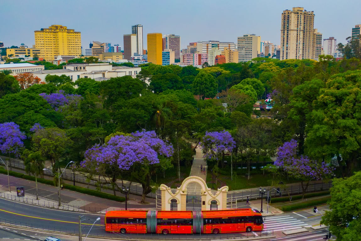 Skyline de Curitiba ao entardecer, com prédios e áreas verdes em destaque