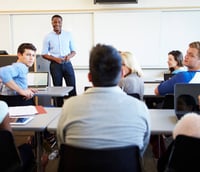 Sala de aula universitária moderna, com professor ministrando aula e estudantes atentos