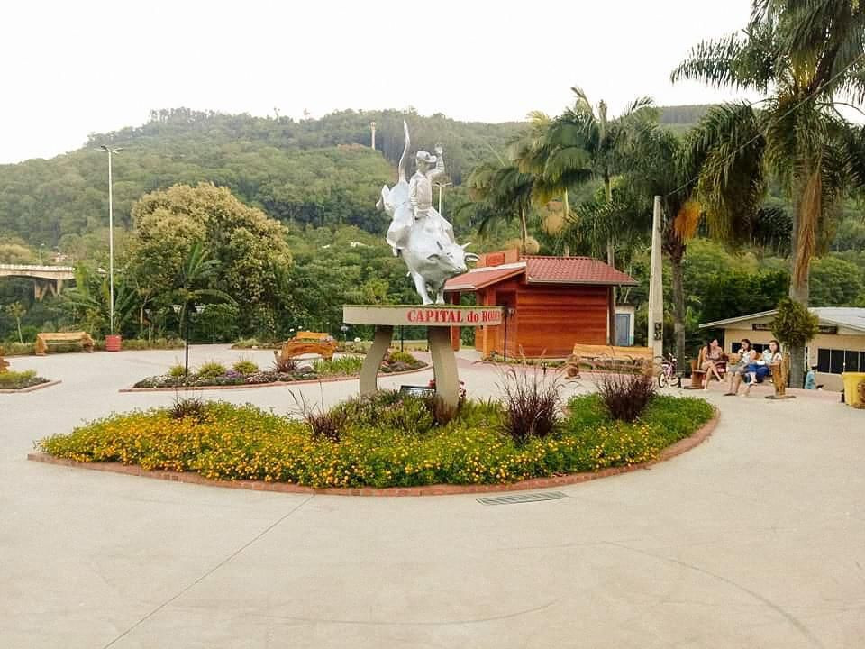 Centro de Ibicaré (SC), com área pública ajardinada e esculturas; ao fundo, construções baixas e céu azul