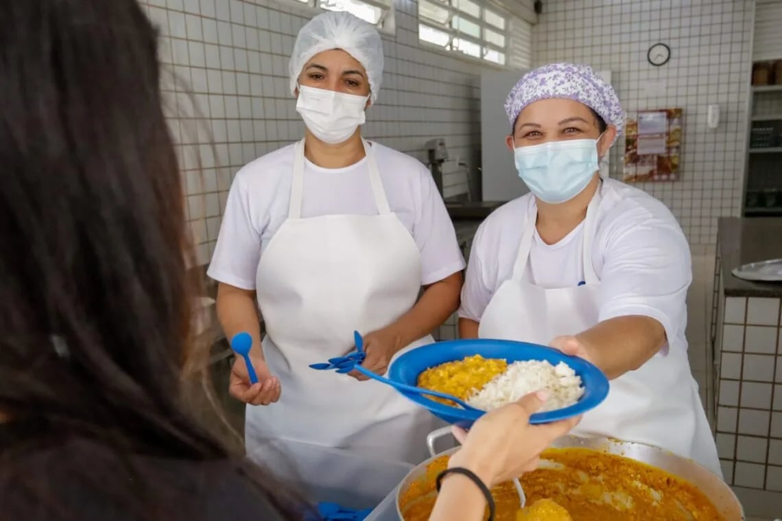 Cozinha institucional com equipe preparando refeições