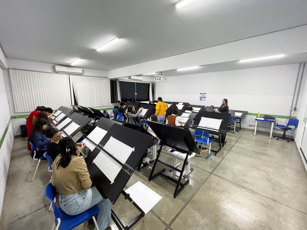 Estúdio de arquitetura universitário com pranchetas, maquetes e estudantes em atividade