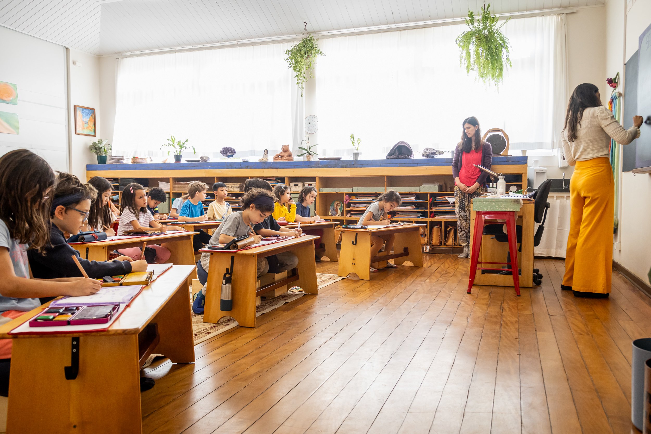 Sala de aula no Brasil, com professora ao quadro e alunos de costas
