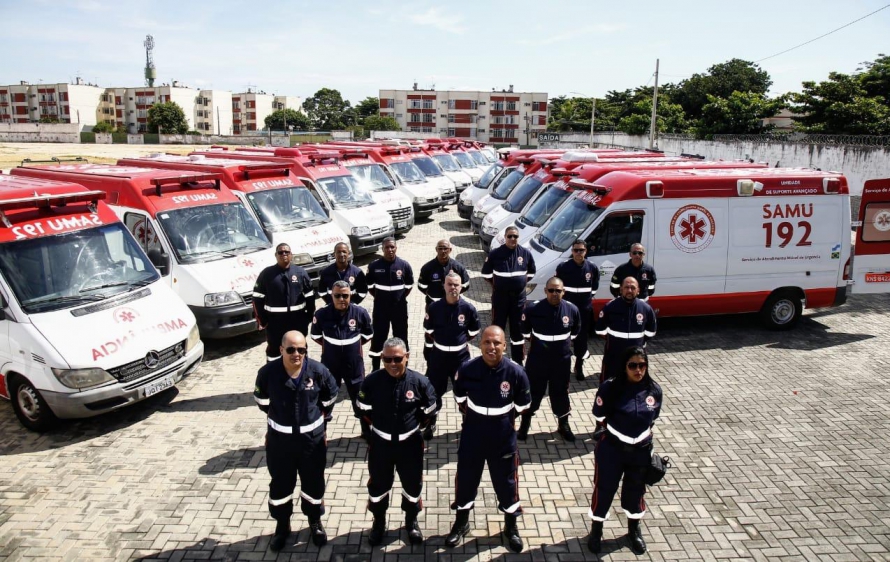 Equipe do SAMU 192 em frente às ambulâncias de emergência, em cenário urbano.