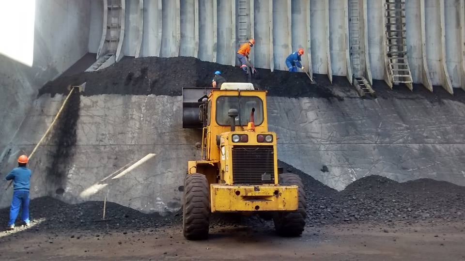 Trabalhadores em operações portuárias com cargas e equipamentos ao fundo