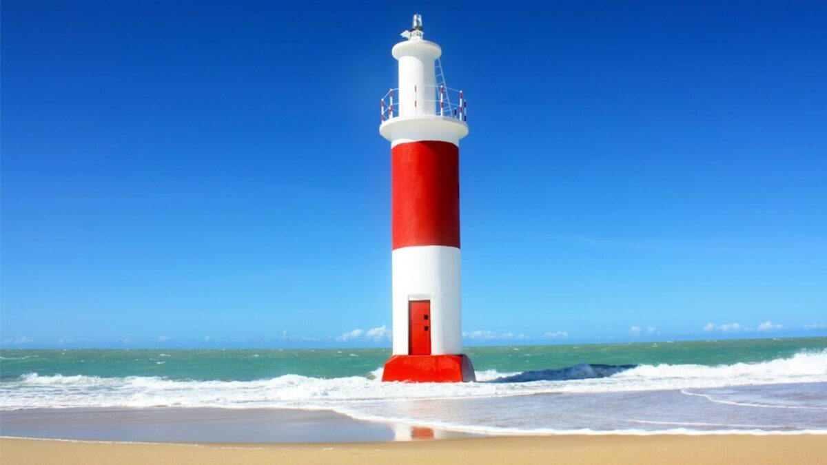 Paisagem de Galinhos RN com farol, praia e céu azul, em fotografia horizontal