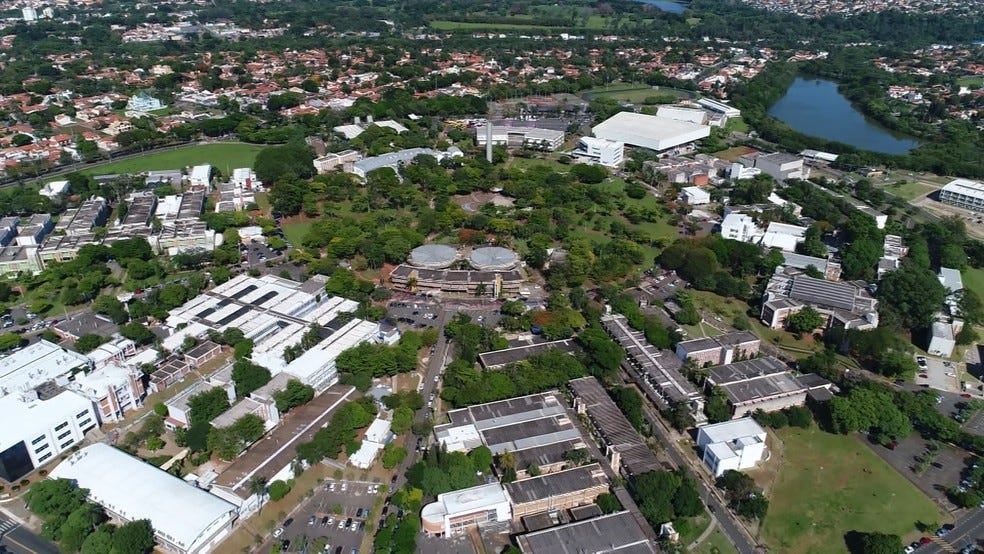 Vista aérea do campus da Unicamp ao entardecer, com prédios e áreas verdes