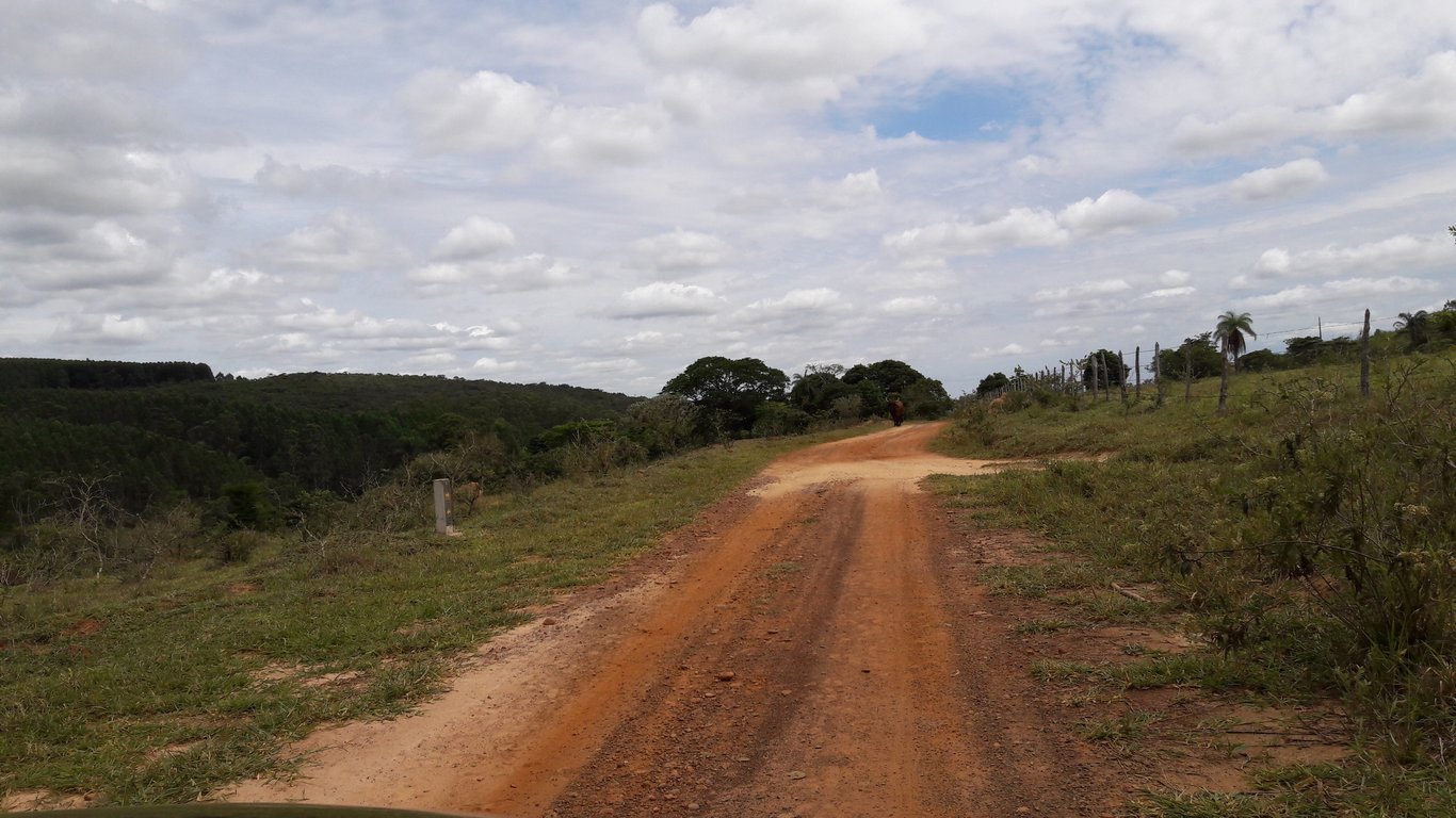 Estrada rural de terra com horizonte montanhoso no interior de Minas Gerais