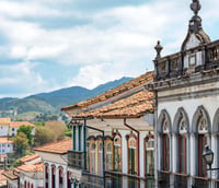 Vista histórica de Ouro Preto MG, com igrejas barrocas e morros ao fundo.