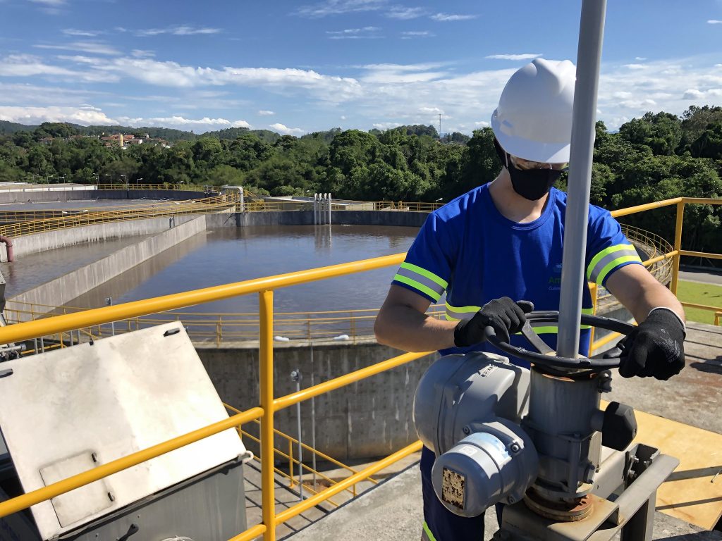 Estruturas de saneamento com tanques de tratamento de água/esgoto e profissional em operação