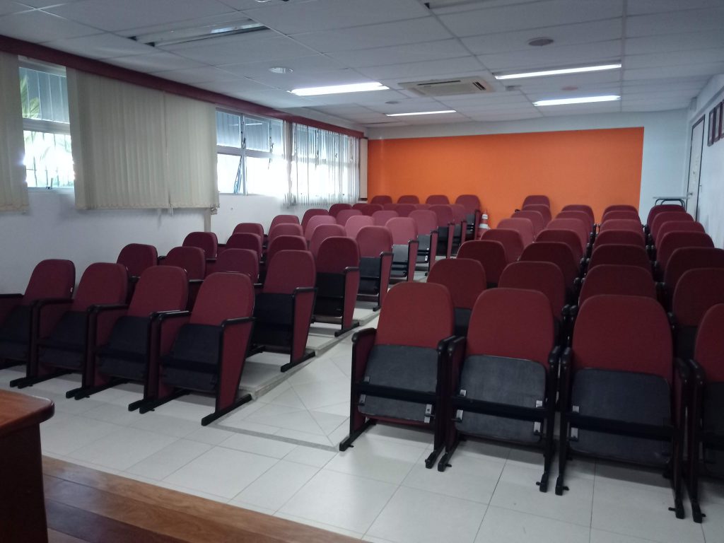 Sala de aula universitária vazia com cadeiras organizadas e projetor.