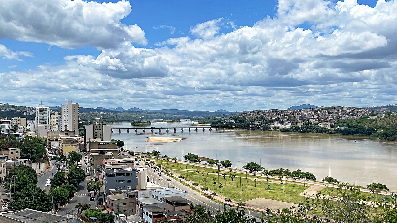 Vista aérea de uma cidade do interior no Noroeste capixaba, com colinas verdes ao fundo, ao pôr do sol