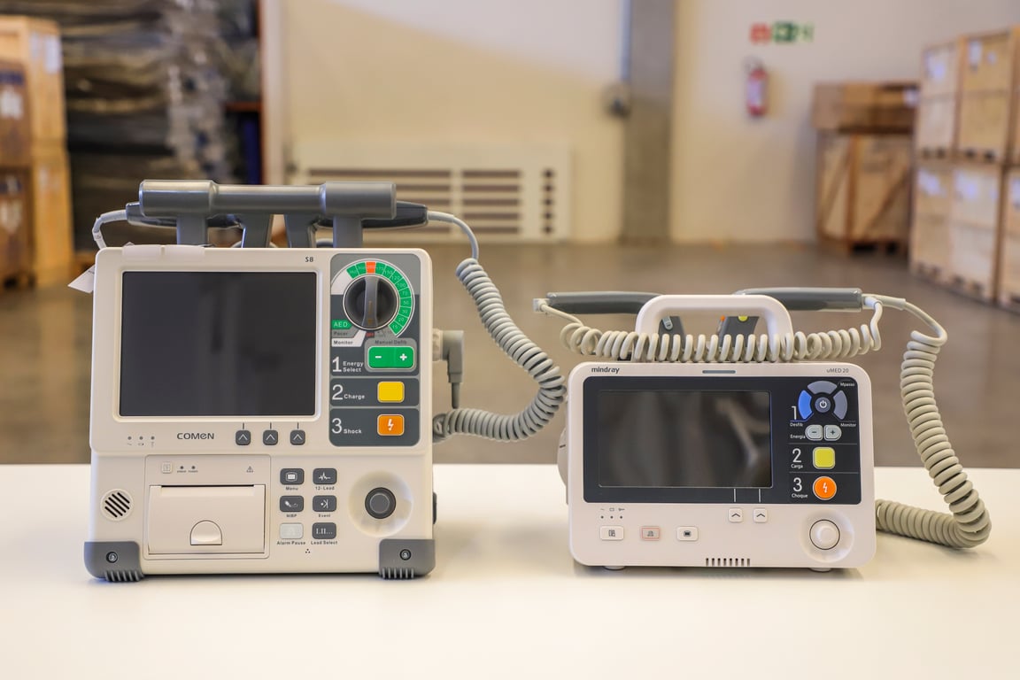 Monitores cardíacos em ambiente de urgência, com cabos e telas acesas em destaque.