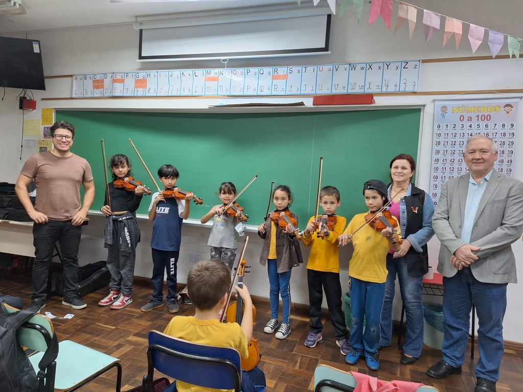 Aula de musicalização com crianças e professor em ambiente escolar, com instrumentos de cordas