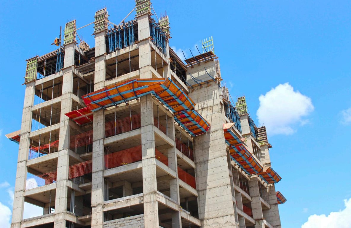 Canteiro de obras com estrutura em concreto e andaimes, céu claro