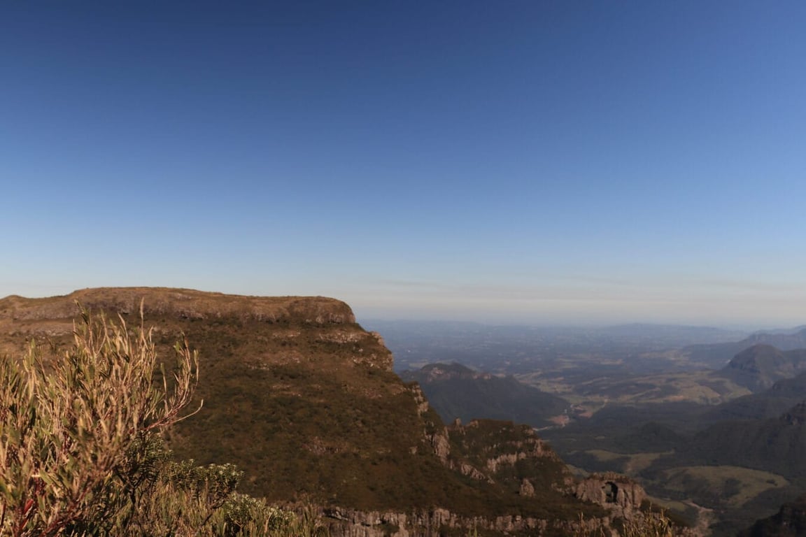 Paisagem do Oeste Catarinense ao entardecer, com morros verdes ao fundo e céu azul claro. Cena tranquila e natural do interior.