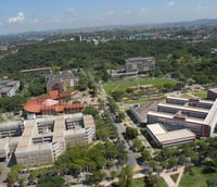 Vista aérea do campus Pampulha da UFMG em Belo Horizonte, mostrando prédios e áreas verdes.