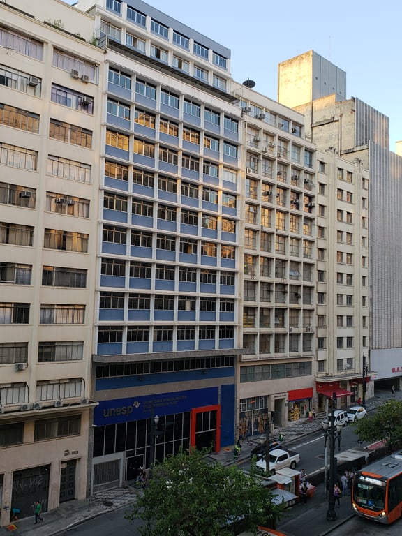 Edifícios do campus da Unesp em Ilha Solteira, com cores azul e vermelha, árvores e circulação de estudantes em dia ensolarado