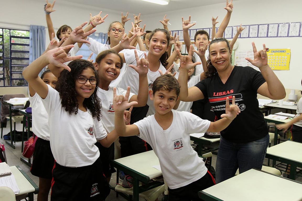 Atividade de Libras em sala de aula, com crianças e professora sinalizando