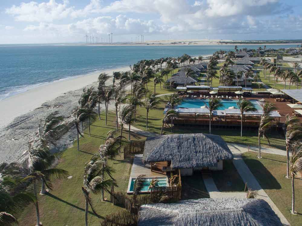 Vila de praia com coqueiros, bangalôs e mar ao fundo no litoral leste do Ceará