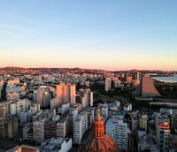 Vista aérea de Porto Alegre ao entardecer, com o Lago Guaíba ao fundo.
