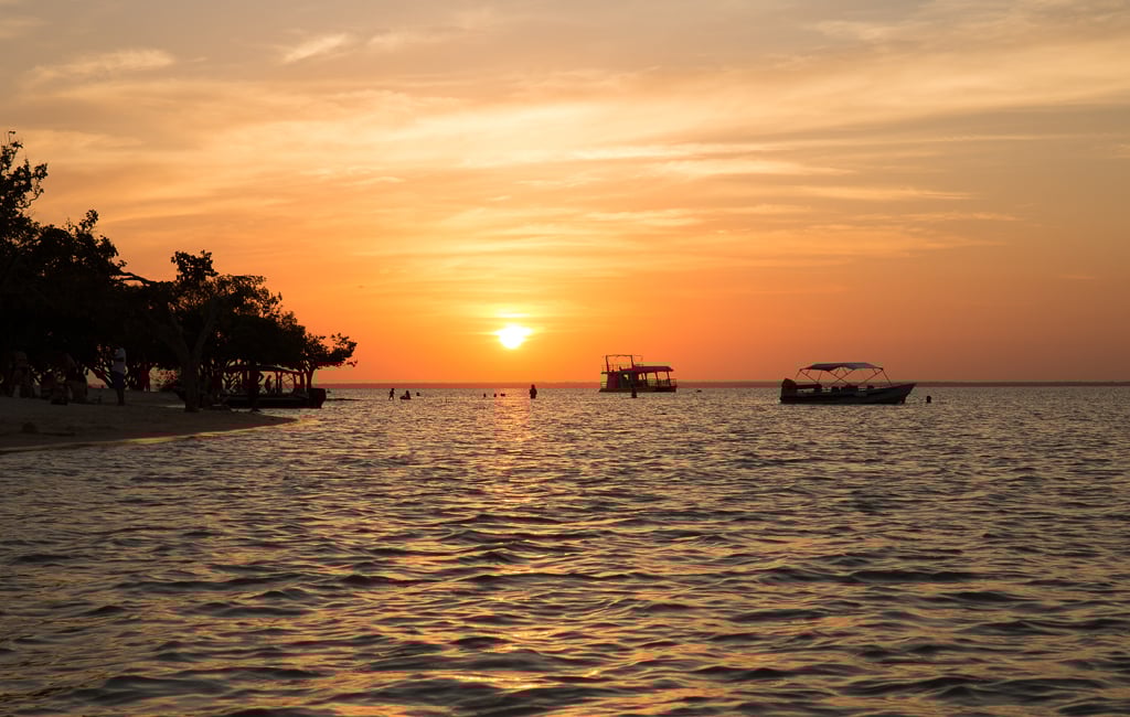 Orla de Santarém com o Rio Tapajós ao pôr do sol; barcos ancorados e vegetação ribeirinha