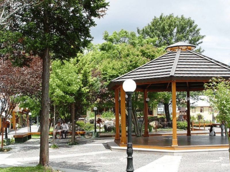 Praça com coreto, árvores e moradores, cenário típico de cidade do interior do RS