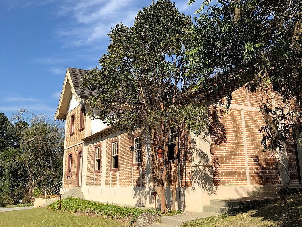 Paisagem de Rancho Queimado, SC, com casa em estilo enxaimel e vegetação de serra
