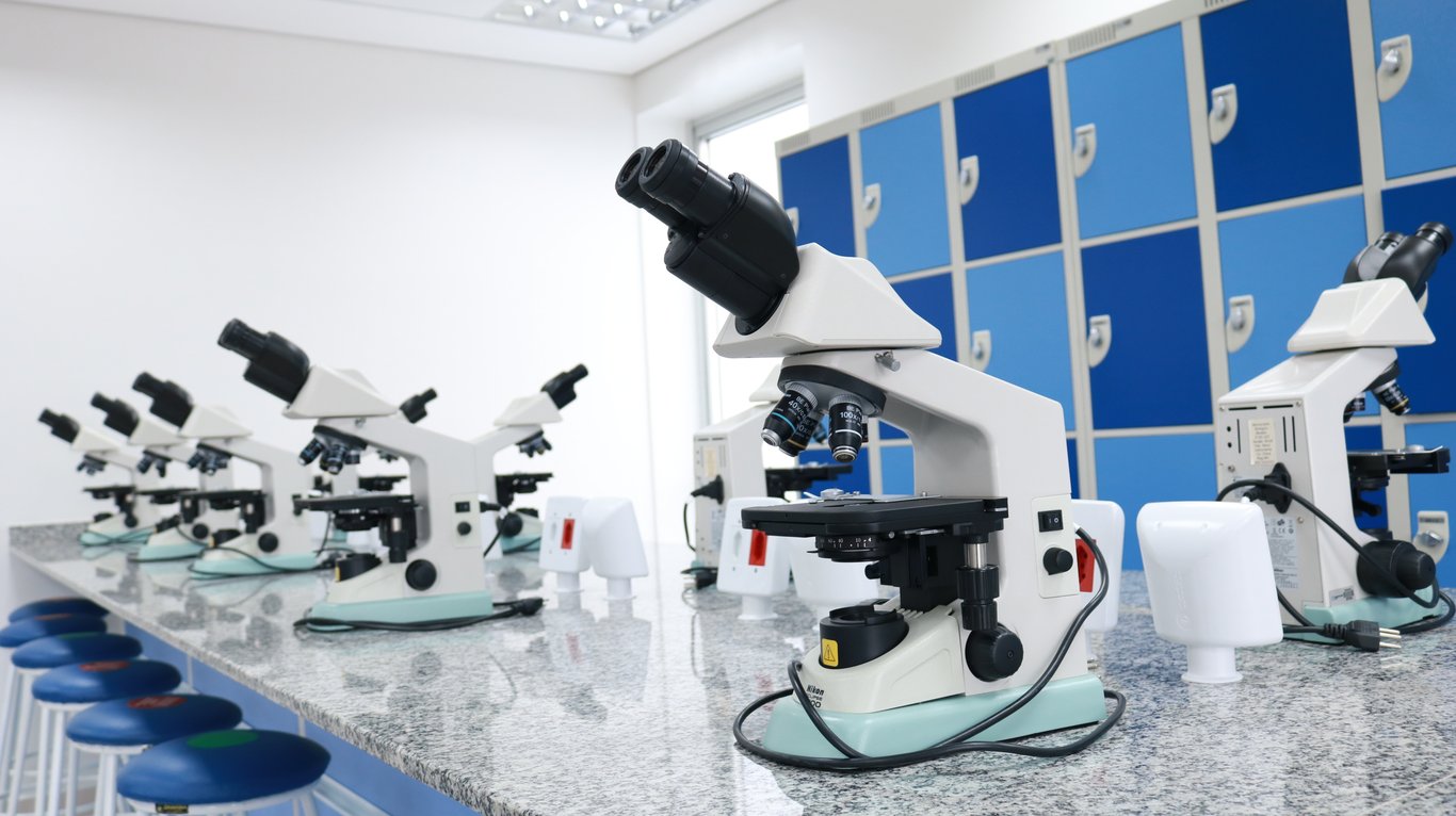 Laboratório com microscópios alinhados sobre bancada