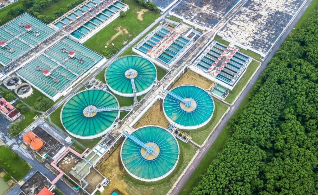 Estação de tratamento de água vista do alto, com tanques circulares e áreas verdes — imagem ilustrativa