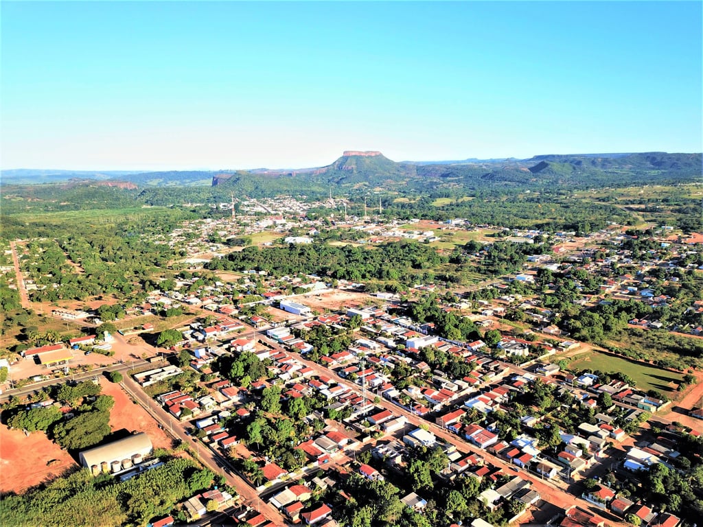 Vista aérea de Poxoréu (MT), com a paisagem urbana e serras ao fundo.