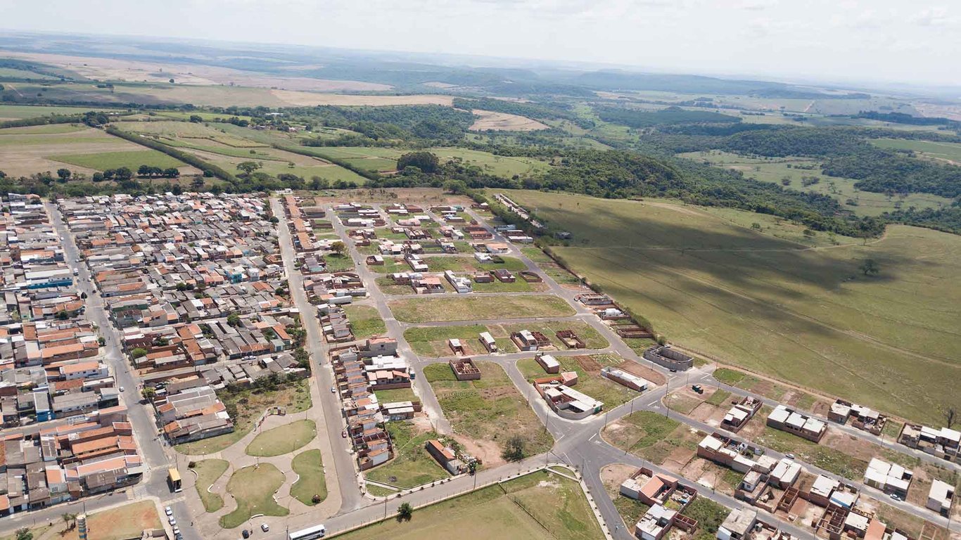 Vista aérea urbana de Ibaté (SP), com bairro residencial e áreas verdes ao fundo