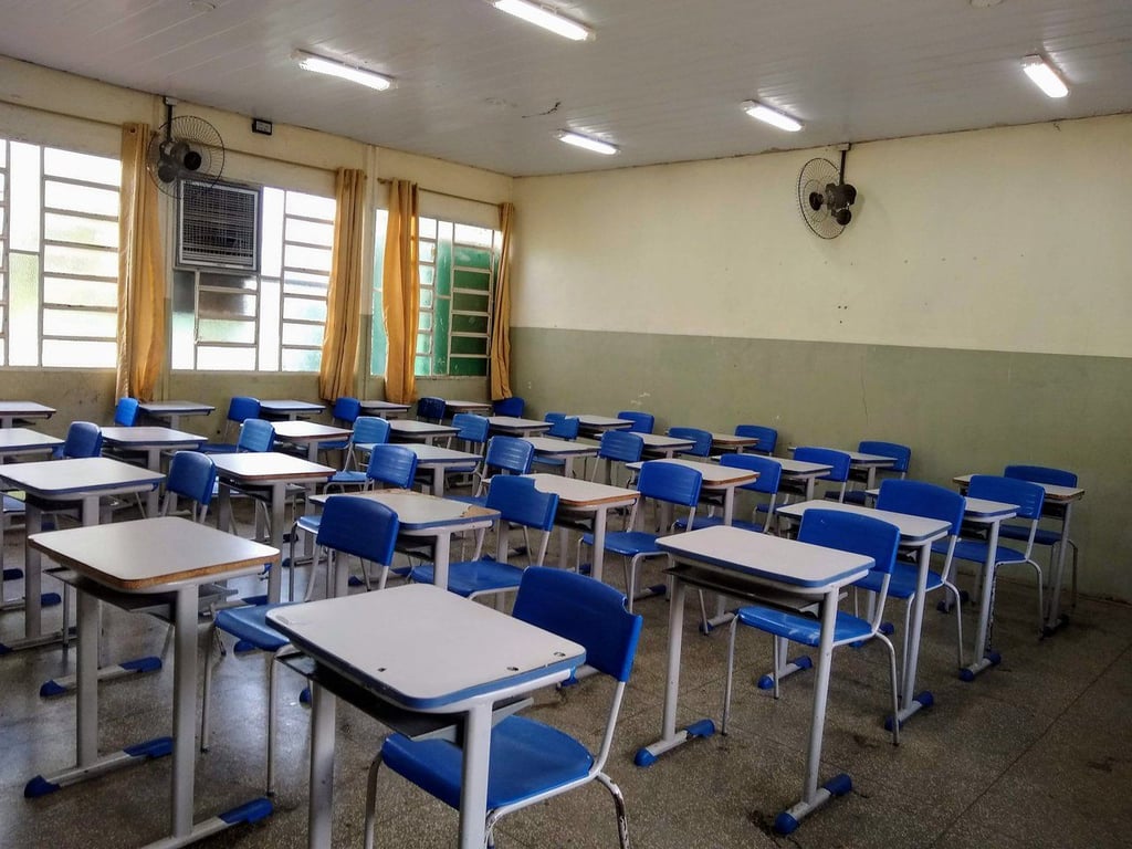 Sala de aula de escola pública no RS, com carteiras e quadro-negro, em luz natural