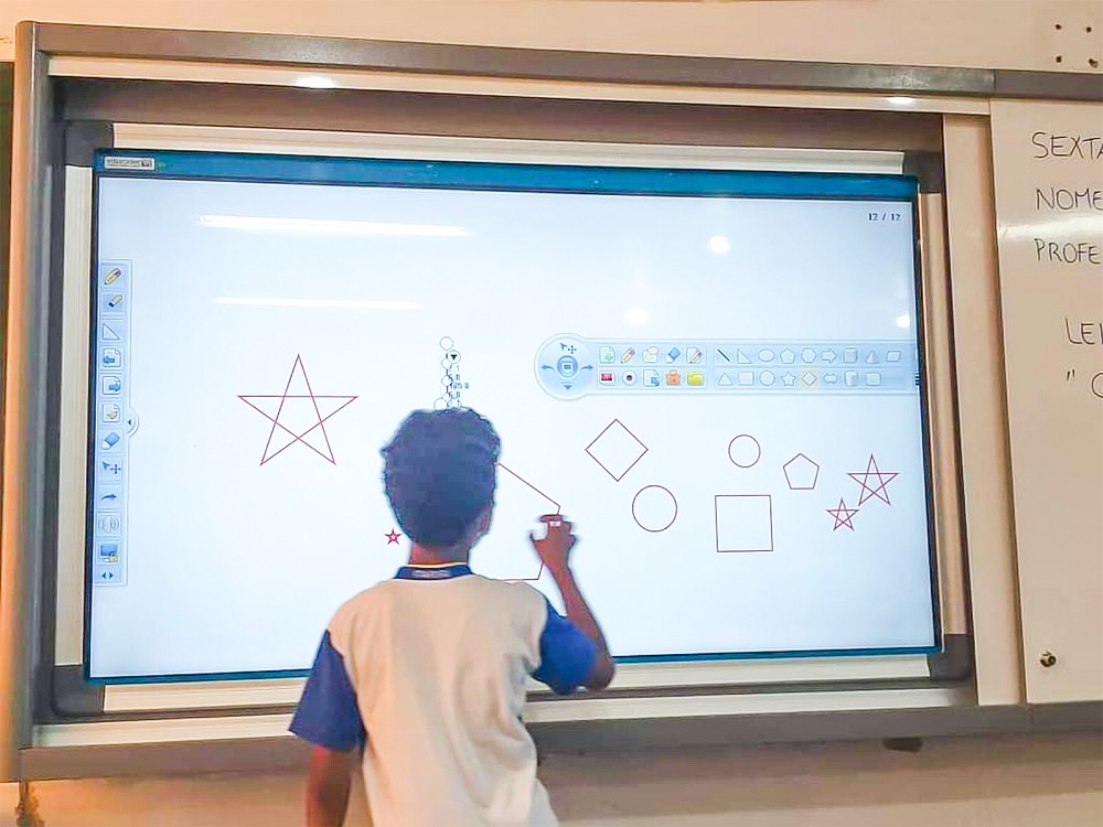 Ambiente de sala de aula técnica com quadro digital e computadores