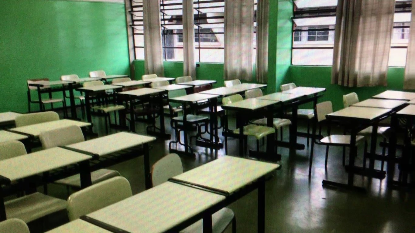 Sala de aula de escola pública com carteiras organizadas e luz natural